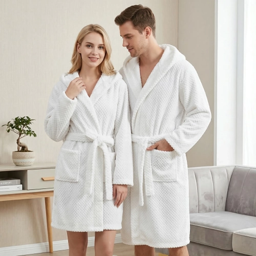Uśmiechnięta para w jasnym pokoju ubrana w grube białe szlafroki kąpielowe z kapturem z miękkiej mikrofibry