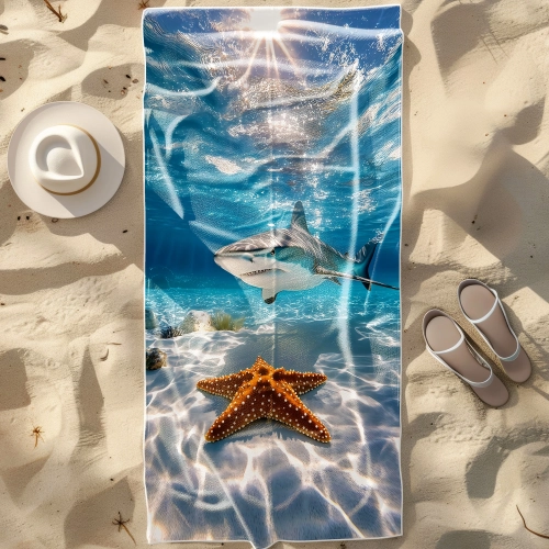 Duży ręcznik plażowy XXL z mikrofibry z fotorealistycznym rekinem i rozgwiazdą pod wodą, rozłożony na piasku obok kapelu