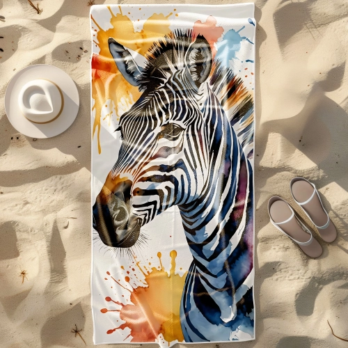 Duży ręcznik plażowy XXL z mikrofibry z motywem akwarelowej zebry z plamami farby, rozłożony na piasku obok kapelusza