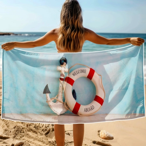 Kobieta na plaży trzymająca za plecami rozłożony duży ręcznik XXL z kołem ratunkowym Welcome Aboard