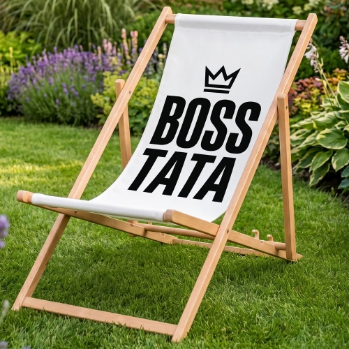 Drewniany leżak z białym siedziskiem i czarnym napisem BOSS TATA z koroną, stojący na zielonym trawniku w ogrodzie na tl
