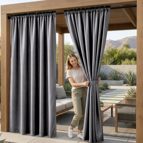 Kobieta na tarasie pod drewnianą pergolą upinająca wodoodporne ciemnoszare zasłony ogrodowe