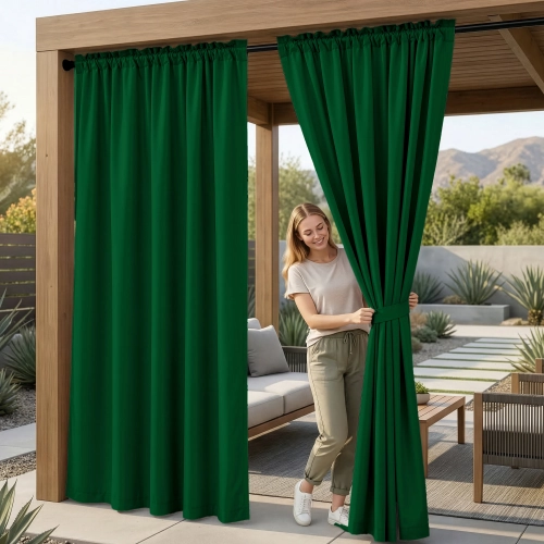 Kobieta na tarasie pod drewnianą pergolą upinająca wodoodporne ciemnozielone zasłony ogrodowe