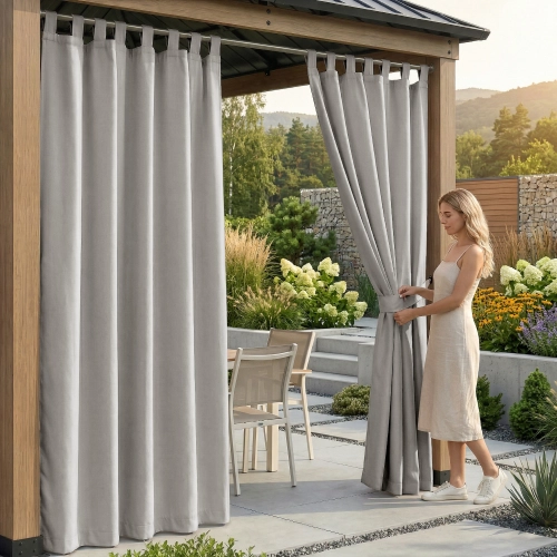 Kobieta pod drewnianą pergolą upinająca jasnoszarą, wodoodporną zasłonę ogrodową na szelkach materiałowym paskiem