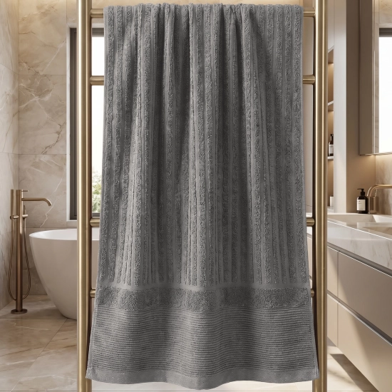 Ciemnoszary prążkowany ręcznik ARIA wiszący na złotym grzejniku łazienkowym, luksusowa łazienka