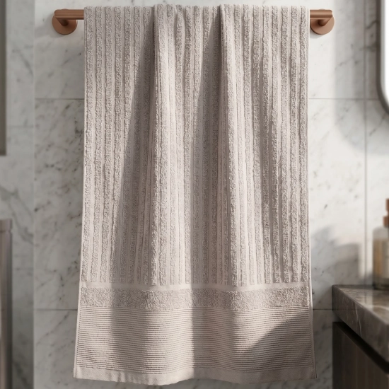 Jasnoszary chłonny ręcznik ARIA z elegancką bordiurą wiszący na drążku w nowoczesnej łazience.