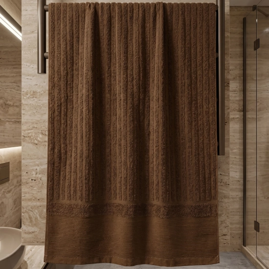 Brązowy miękki ręcznik ARIA w prążki na czarnym grzejniku drabinkowym na tle beżowego marmuru