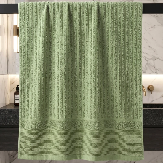 Szałwiowy zielony ręcznik bawełniany ARIA wiszący w eleganckiej ciemnej łazience ze złotymi detalami.