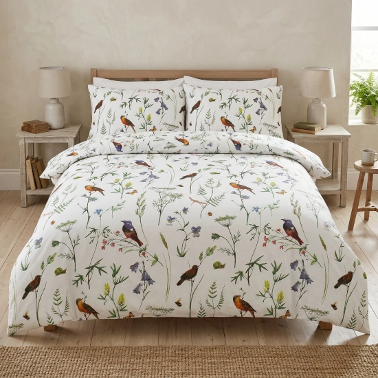 Kompleksowy widok na łóżko w jasnej sypialni, zaścielone pościelą z bawełny premium J&W wzór Łąka Botaniczna.