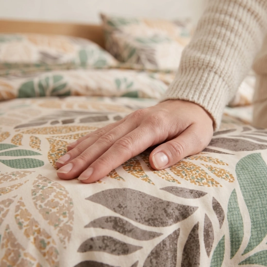 Zbliżenie na gładką strukturę tkaniny bawełnianej i organiczny nadruk liści w kolorach beżu, szałwii i ochry