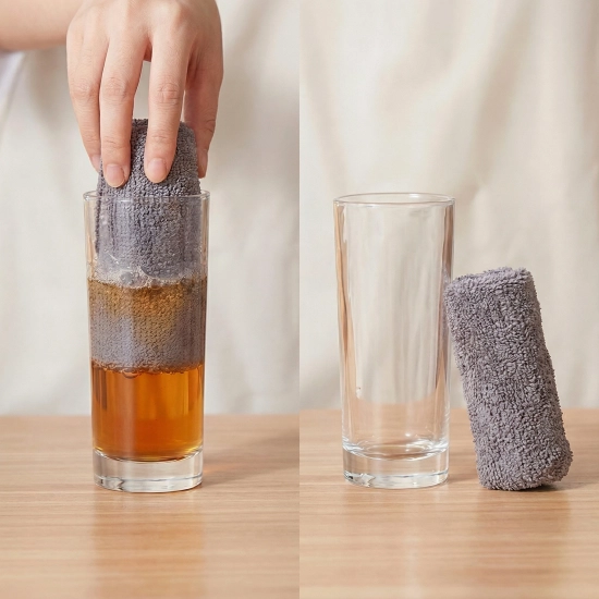 Zdjęcie przed i po obrazujące chłonność: po lewej dłoń wciska zrolowaną szarą ściereczkę do wysokiej szklanki z brązowym płynem, po prawej pusta szklanka i stojąca obok mokra ściereczka, która wchłonęła całą ciecz.
