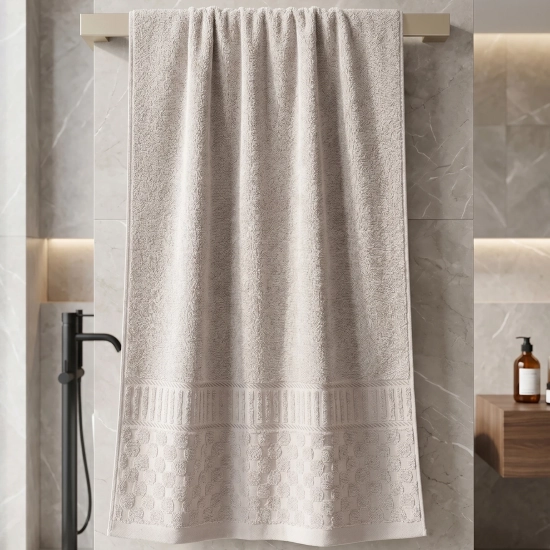 Jasnoszary ręcznik do rąk i twarzy z wytłaczanym wzorem wiszący na wieszaku w eleganckiej łazience