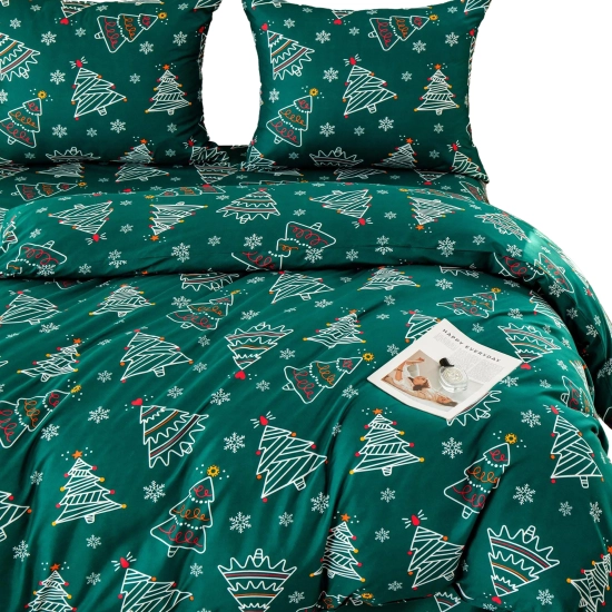 Packshot rozłożonej zielonej pościeli w choinki i śnieżynki z dwiema poduszkami na białym tle