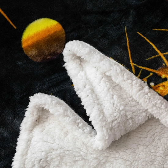 Zbliżenie na puszysty biały baranek sherpa i czarną mikrofibrę koca z motywem złotej choinki
