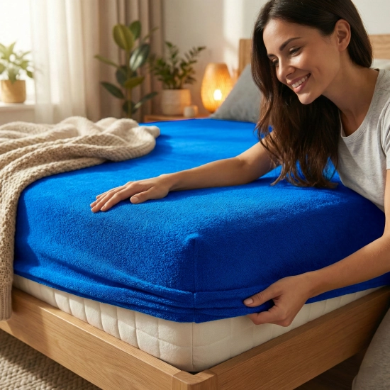 Kobieta zakładająca chabrowe prześcieradło nieprzemakalne frotte z gumką na materac w przytulnej sypialni, polski produc