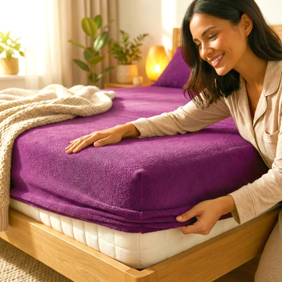 Kobieta zakładająca fioletowe prześcieradło nieprzemakalne frotte z gumką na materac w przytulnej sypialni, polski produ