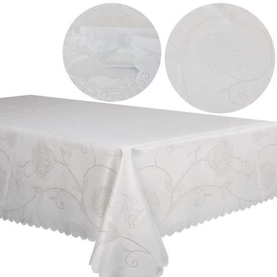 Stół z białym obrusem świątecznym w srebrne gwiazdki i choinką w tle