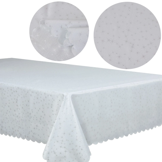 Stół udekorowany białym obrusem w srebrne gwiazdki i świąteczną zastawą