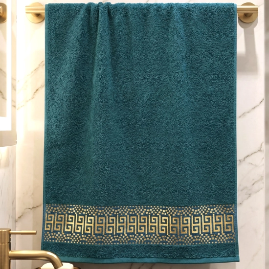 Szmaragdowy elegancki ręcznik bawełniany PERLA ze złotą bordiurą wiszący na relingu.