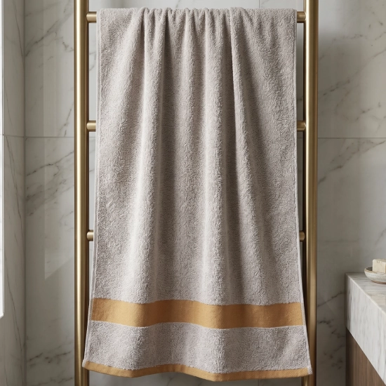 Jasnoszary chłonny ręcznik do twarzy PRIMO z kolekcji barw ziemi na złotym wieszaku w eleganckiej łazience.