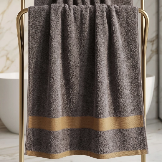 Ciemnoszary bawełniany ręcznik do rąk PRIMO 50x100 na złotym stojaku obok umywalki.