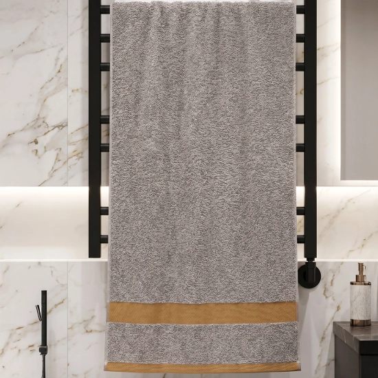 Szary ręcznik do twarzy i rąk PRIMO bawełniany na czarnym, drabinkowym grzejniku łazienkowym na tle marmuru.