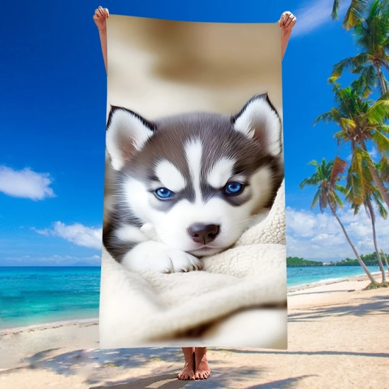 Rozłożony pionowo ręcznik plażowy z mikrofibry z uroczym motywem pieska rasy husky zaprezentowany na tropikalnej plaży z palmami