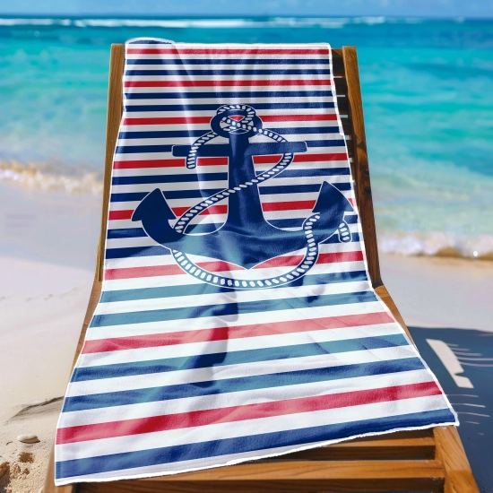 Ręcznik plażowy w marynarskie pasy z kotwicą zawieszony na leżaku na rajskiej plaży z jasnym piaskiem.