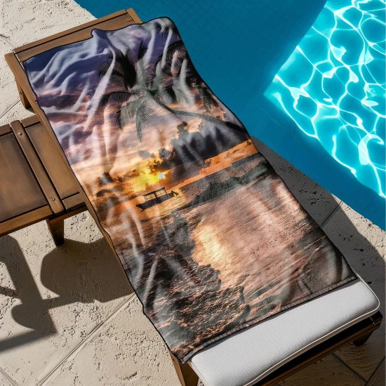 Ogromny ręcznik plażowy z motywem tropikalnego raju rozłożony na drewnianym leżaku stojącym przy błękitnym basenie - TwójDomNa5.pl