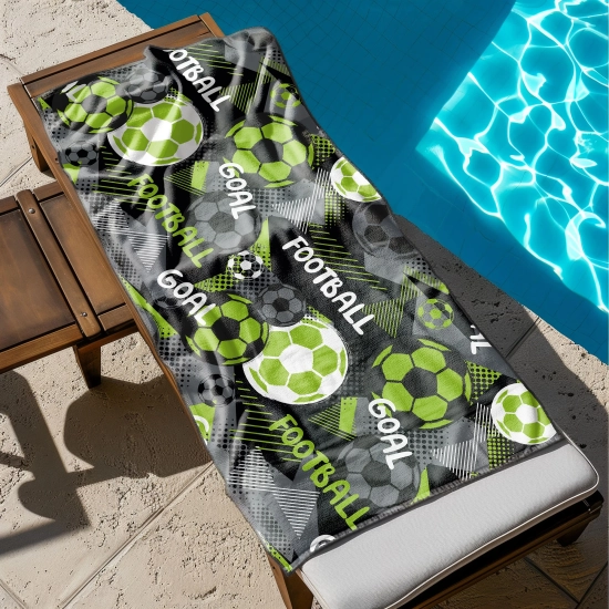 Ogromny ręcznik plażowy XXL z neonowym wzorem football rozłożony w całości na drewnianym leżaku