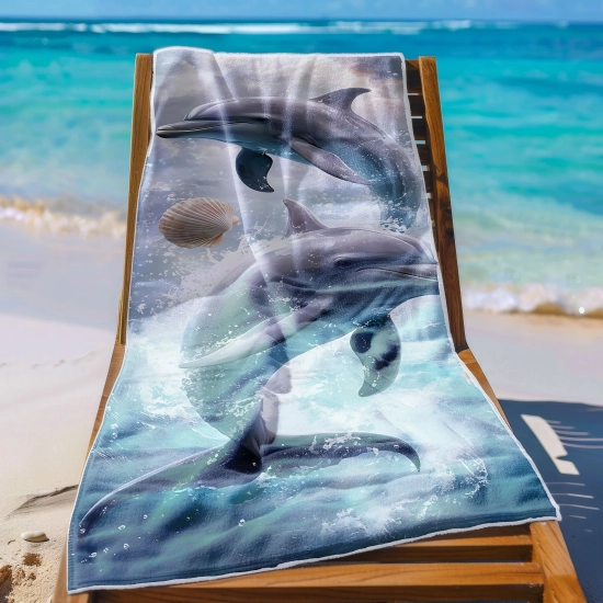 Ręcznik plażowy XXL 100x180 z fotorealistyczną grafiką delfinów rozłożony na leżaku na tle lazurowej wody - TwójDomNa5.pl