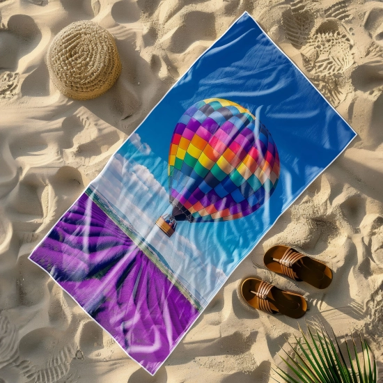 Wielki ręcznik plażowy Serena z idyllicznym krajobrazem letnim, leżący na piaszczystej plaży obok kapelusza