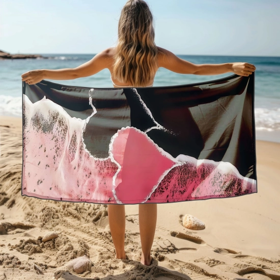 Kobieta stojąca tyłem trzymająca rozłożony gigantyczny ręcznik plażowy z mikrofibry z różowym sercem