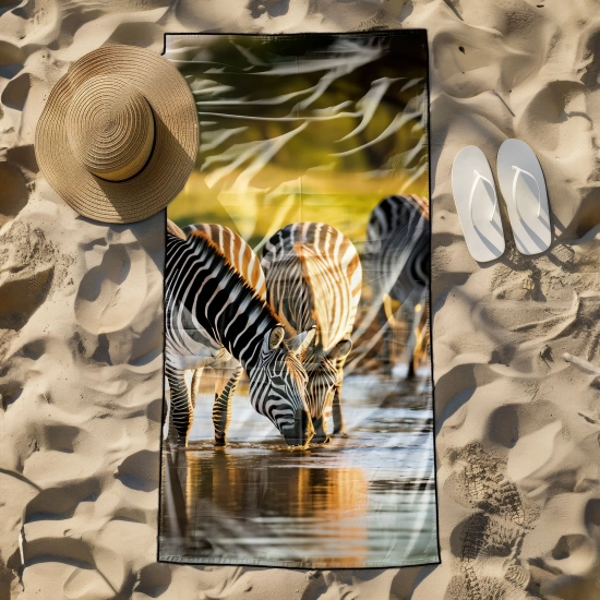 Odporny na piasek ręcznik podróżny o wzorze zebr w złotej godzinie leżący obok słomkowego kapelusza i białych klapek