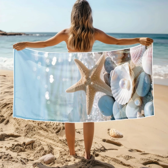 Modelka na plaży trzymająca rozłożony ręcznik z mikrofibry ze wzorem rozgwiazdy i perły