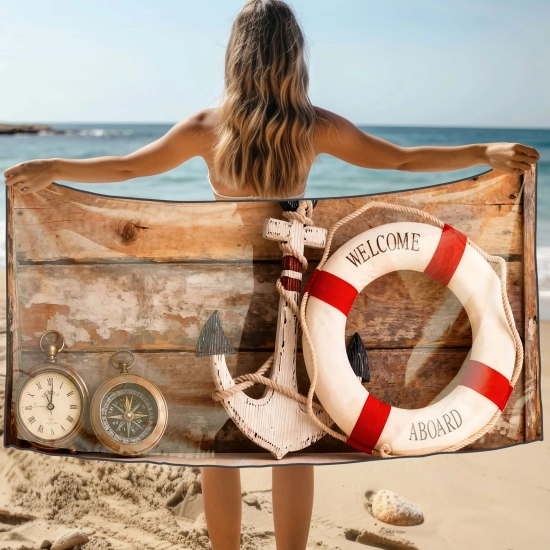 Kobieta na plaży trzyma za plecami ręcznik z kołem ratunkowym i kompasem na tle drewna - TwójDomNa5.pl