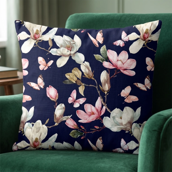 Kwadratowa bawełniana poszewka we wzór kwitnących magnolii i motyli, elegancko ułożona na ciemnozielonym welurowym fotelu