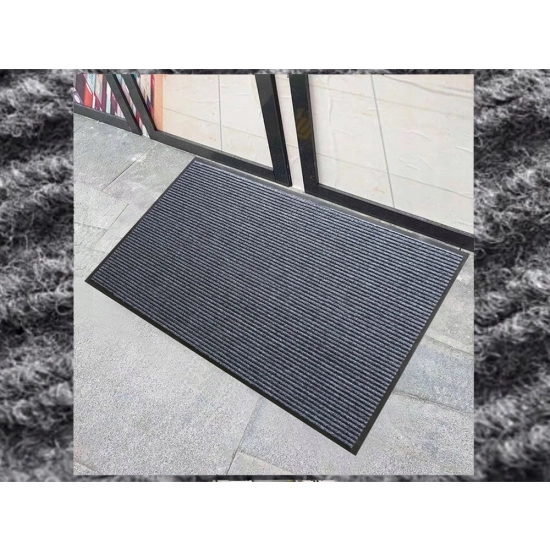 Szara podgumowana wycieraczka 60x90 cm umieszczona pod drzwiami wejściowymi do domu