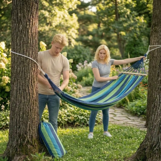 Para wieszająca hamak turystyczny między drzewami w parku