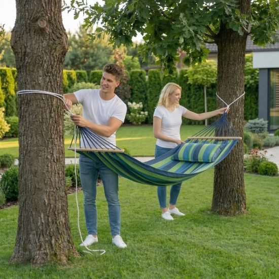 Zawieszanie hamaka turystycznego z poduszką między drzewami na działce
