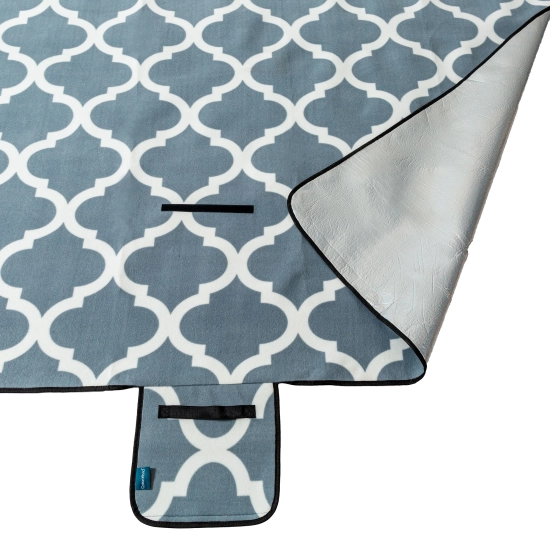 Odwinięty róg koca piknikowego prezentujący aluminiową warstwę izolacyjną chroniącą przed chłodem i wilgocią.