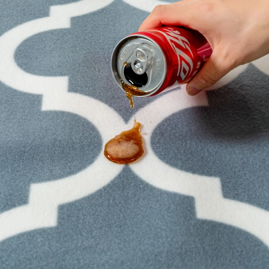 Ciemny napój wylewany z puszki, który perli się na polarowej powierzchni koca piknikowego.