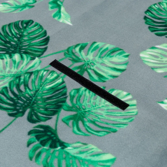 Zbliżenie na mocny, czarny rzep mocujący na polarowej powierzchni w modny wzór zielonych liści monstery.