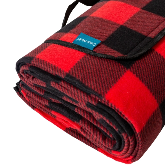 Zbliżenie na złożony koc piknikowy z motywem w kratę, z widoczną czarną lamówką i solidnym zapięciem.