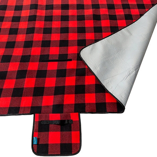 Odwinięty róg koca piknikowego prezentujący aluminiową warstwę izolacyjną chroniącą przed chłodem i wilgocią