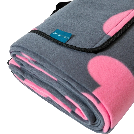 Zbliżenie na złożony koc piknikowy w serduszka, z widoczną czarną lamówką i solidnym rzepem.