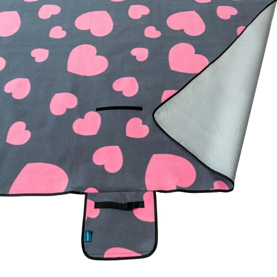 Odwinięty róg koca piknikowego prezentujący aluminiową warstwę od spodu chroniącą przed chłodem.