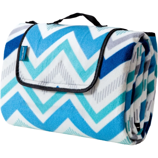 Złożony w kostkę koc piknikowy WONDER w morsko-niebieskie zygzaki na białym tle, z czarną rączką do przenoszenia.