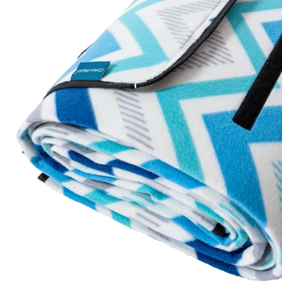 Zbliżenie na złożony koc piknikowy ze wzorem chevron, z widoczną czarną lamówką i solidnym rzepem.