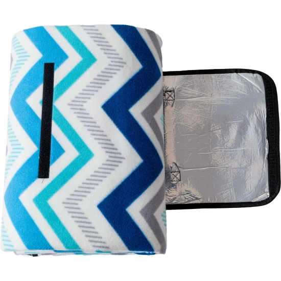 Rozłożona klapka zapięcia koca piknikowego, ukazująca spodnią warstwę wykonaną ze srebrnej, wodoodpornej folii aluminiowej.